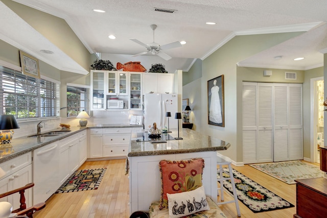 kitchen with white appliances, light hardwood / wood-style floors, white cabinetry, and lofted ceiling