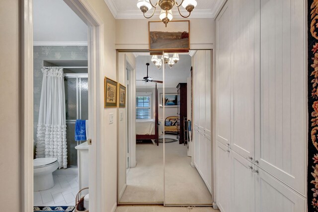 corridor with an inviting chandelier, ornamental molding, and light colored carpet