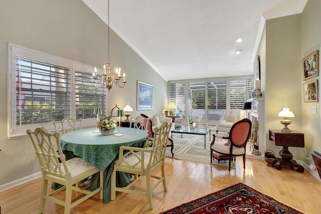 dining space featuring ornamental molding, lofted ceiling, a notable chandelier, and light wood-type flooring