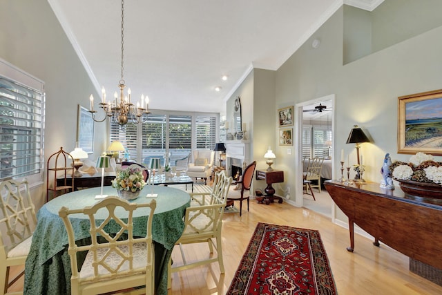 dining area featuring crown molding, ceiling fan with notable chandelier, high vaulted ceiling, and light wood-type flooring