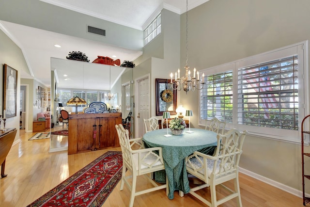 dining space featuring a notable chandelier, ornamental molding, lofted ceiling, and light wood-type flooring