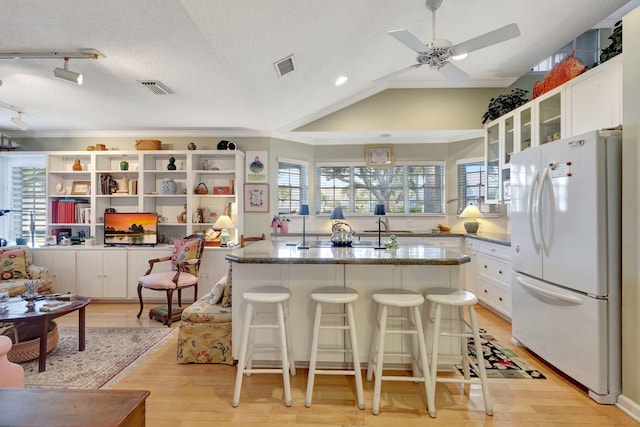 kitchen featuring white cabinetry, light hardwood / wood-style floors, a textured ceiling, and white refrigerator