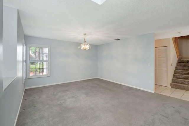 carpeted empty room with a textured ceiling and a chandelier