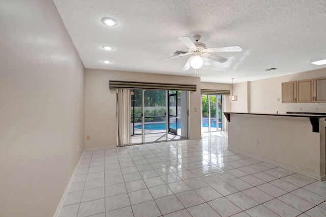 tiled empty room featuring ceiling fan and a textured ceiling