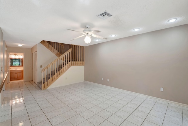 tiled spare room featuring a textured ceiling and ceiling fan