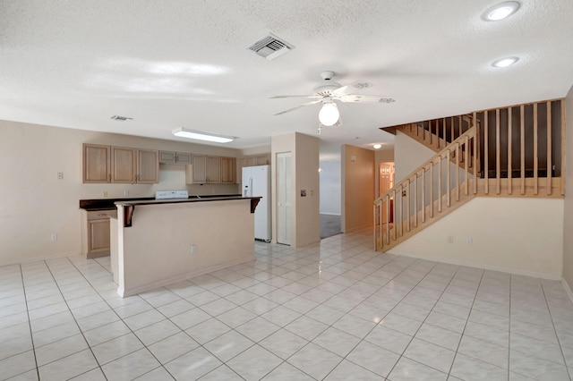 kitchen with ceiling fan, a textured ceiling, white fridge with ice dispenser, and a kitchen island