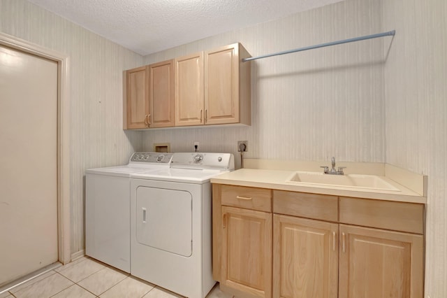 clothes washing area with a textured ceiling, light tile patterned floors, cabinets, sink, and independent washer and dryer