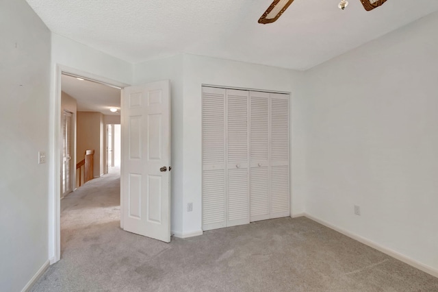 unfurnished bedroom with a textured ceiling, light carpet, ceiling fan, and a closet