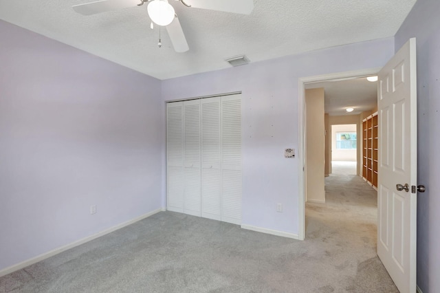 unfurnished bedroom with a closet, a textured ceiling, light carpet, and ceiling fan