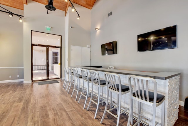 bar featuring high vaulted ceiling, hardwood / wood-style flooring, and beam ceiling