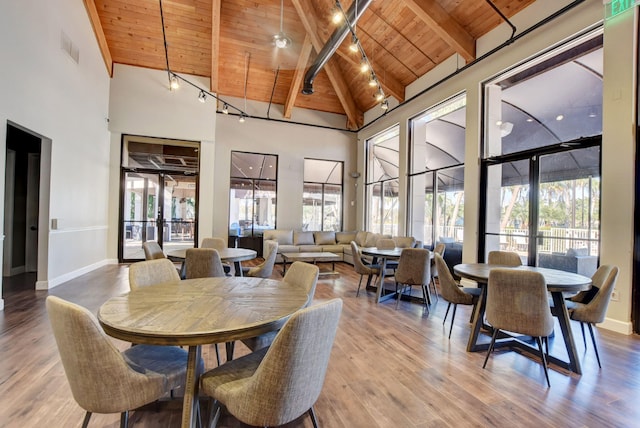 dining area with high vaulted ceiling, wood ceiling, hardwood / wood-style floors, and beam ceiling