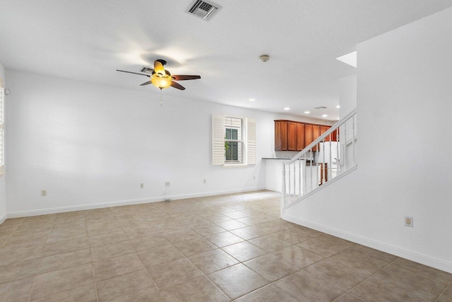 unfurnished living room featuring ceiling fan, light tile patterned flooring, and a textured ceiling