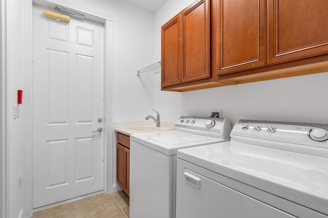 clothes washing area featuring cabinets, light tile patterned floors, sink, and washing machine and clothes dryer