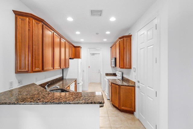 kitchen featuring sink, dark stone countertops, kitchen peninsula, white appliances, and light tile patterned floors