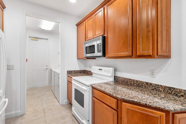 kitchen featuring dark stone countertops, light tile patterned floors, and white electric stove