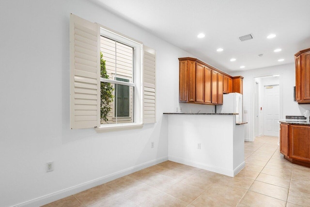 kitchen featuring light tile patterned flooring, white fridge, and dark stone countertops