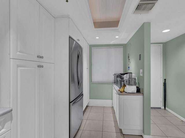 kitchen featuring white cabinetry, a tray ceiling, light tile patterned floors, and stainless steel refrigerator