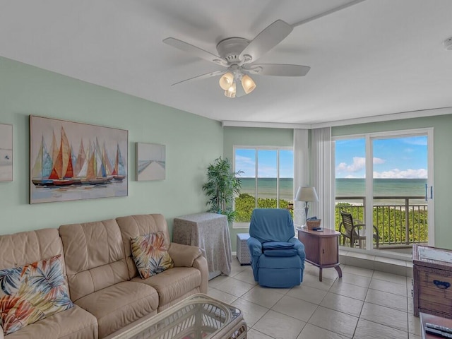 tiled living room featuring a healthy amount of sunlight, a water view, and ceiling fan