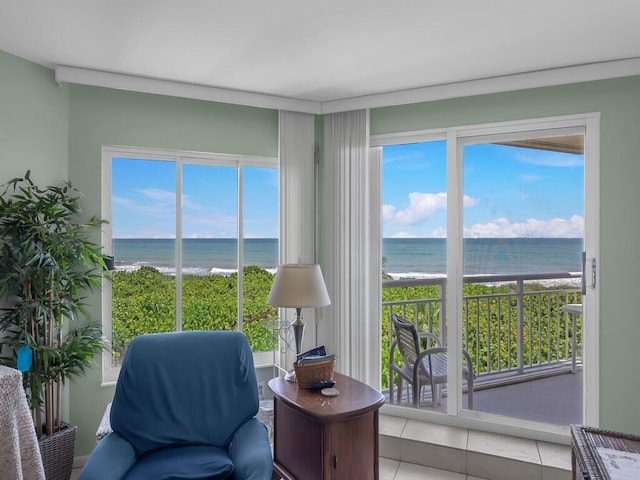 sitting room featuring a water view, a wealth of natural light, tile patterned flooring, and a beach view