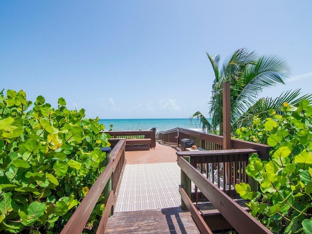 surrounding community with a deck with water view and a beach view