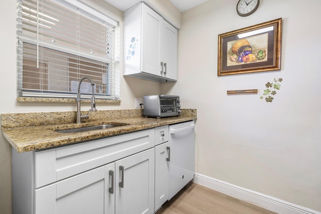 kitchen with dishwasher, stone countertops, white cabinetry, and sink