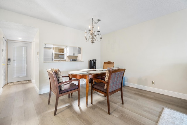 dining space with a textured ceiling, a chandelier, and light hardwood / wood-style flooring