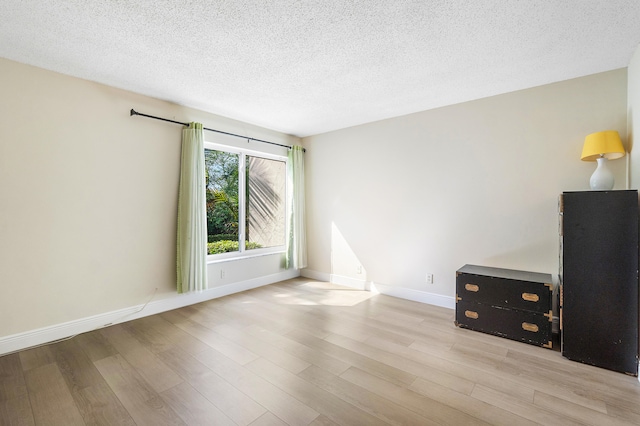 unfurnished room with light hardwood / wood-style floors and a textured ceiling