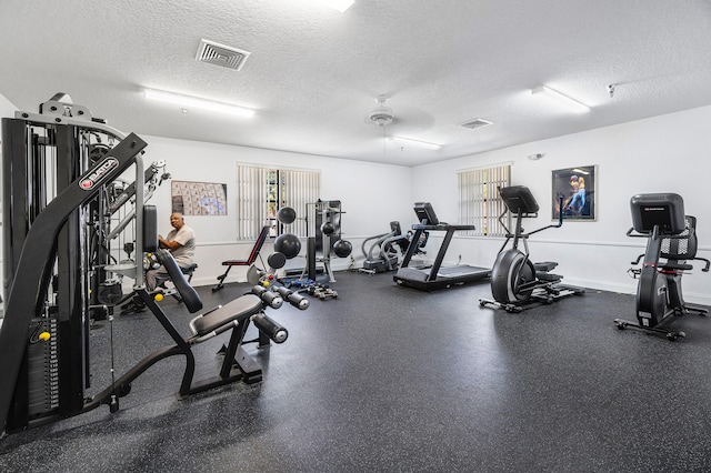 gym featuring a textured ceiling, ceiling fan, and a wealth of natural light