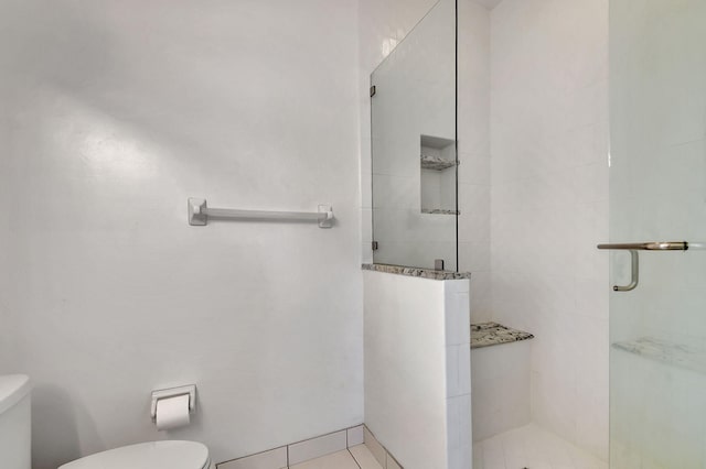 bathroom featuring tile patterned floors, a shower with shower door, and toilet