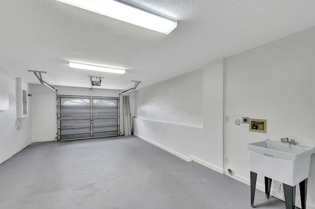 garage featuring electric panel, sink, and a garage door opener