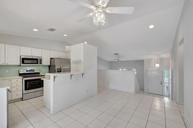 kitchen with a kitchen bar, tasteful backsplash, stainless steel appliances, white cabinetry, and lofted ceiling