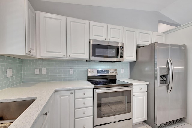 kitchen with white cabinetry, stainless steel appliances, light stone counters, backsplash, and vaulted ceiling