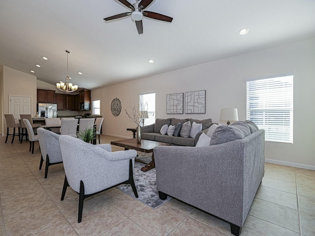 living room with ceiling fan with notable chandelier, vaulted ceiling, and light tile patterned flooring