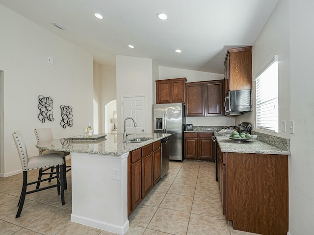 kitchen with a kitchen breakfast bar, sink, a kitchen island with sink, and stainless steel appliances