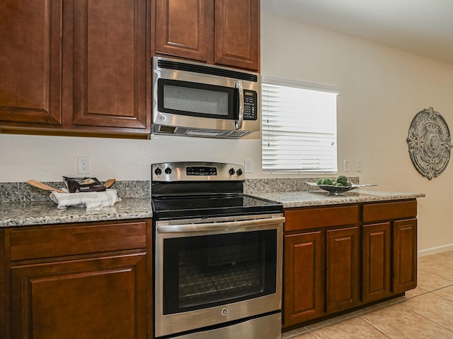 kitchen with light tile patterned flooring, light stone counters, and appliances with stainless steel finishes