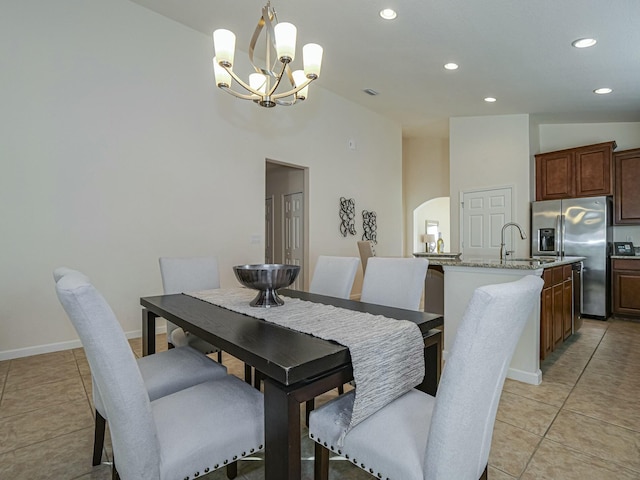 tiled dining room featuring sink, a towering ceiling, and a chandelier