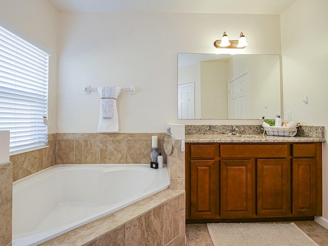 bathroom with vanity, a relaxing tiled tub, and a wealth of natural light