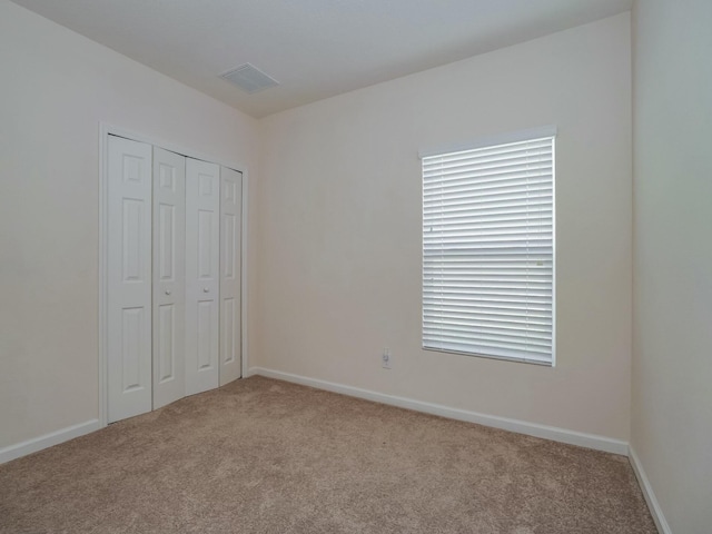 unfurnished bedroom with a closet and light colored carpet