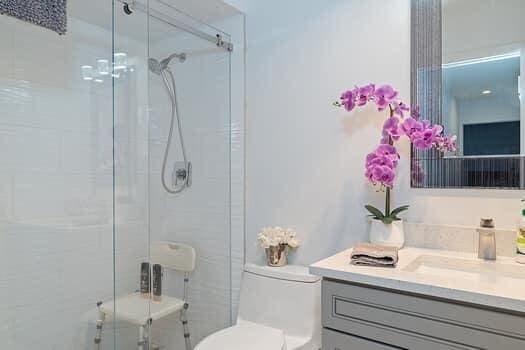 bathroom featuring a shower with door, vanity, and toilet