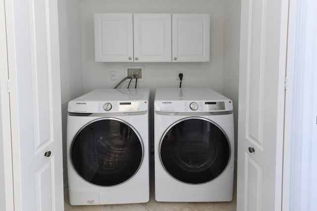 laundry area featuring light tile patterned floors, cabinets, and washing machine and clothes dryer