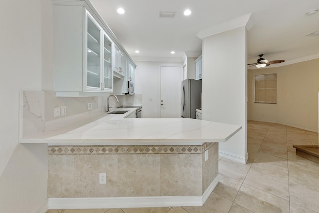 kitchen with light stone counters, stainless steel appliances, kitchen peninsula, and white cabinets