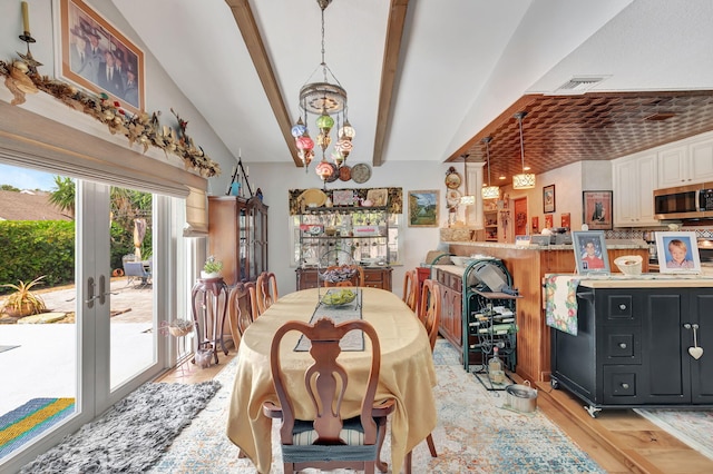 dining space featuring an inviting chandelier, light hardwood / wood-style flooring, bar area, french doors, and lofted ceiling with beams