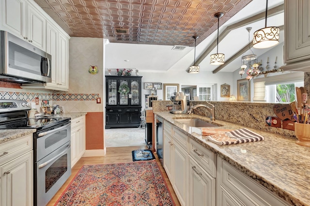 kitchen with light hardwood / wood-style flooring, stainless steel appliances, sink, decorative light fixtures, and light stone counters