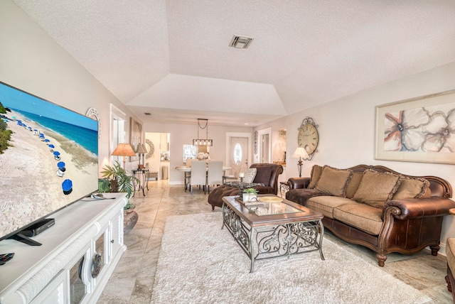 living room with lofted ceiling, a textured ceiling, and a notable chandelier