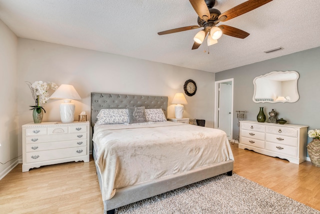 bedroom with light wood-type flooring, a textured ceiling, and ceiling fan