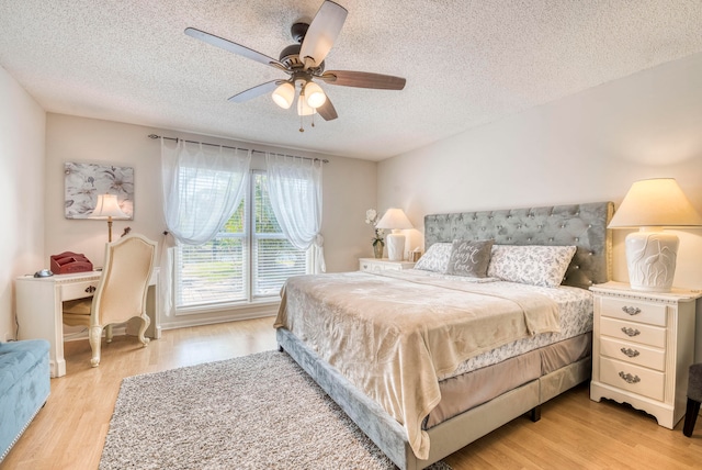 bedroom with a textured ceiling, ceiling fan, and light hardwood / wood-style flooring