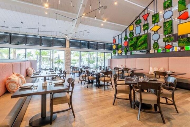 dining area featuring light hardwood / wood-style flooring, track lighting, and a towering ceiling