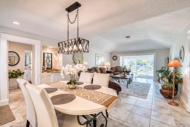 dining area featuring lofted ceiling, a textured ceiling, and a notable chandelier