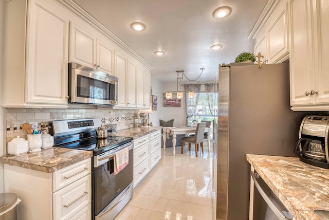 kitchen with stainless steel appliances, white cabinets, light stone counters, and decorative backsplash