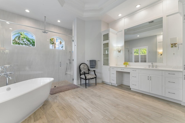 bathroom with a raised ceiling, separate shower and tub, hardwood / wood-style floors, vanity, and ornamental molding